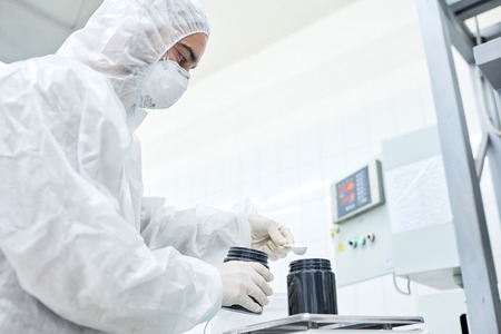 Factory worker adding product to plastic containerの写真素材