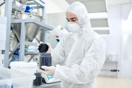 Factory worker closing plastic container with product