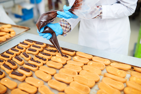 Confectioner decorating pastry using icing bagの写真素材