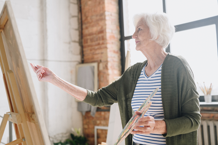Senior Woman Painting in Art Studioの写真素材