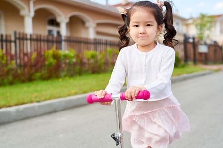 Little Asian Girl Riding Scooterの写真素材