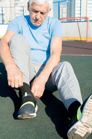 Senior Man Tying Shoes on Trackの写真素材