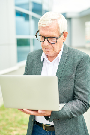Elderly entrepreneur browsing laptopの写真素材