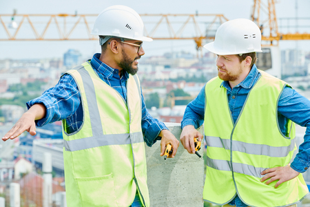 Mixed race construction engineer talking to coworkerの写真素材
