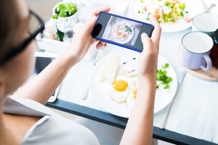 Woman Taking Photo of Food  in Cafeの写真素材