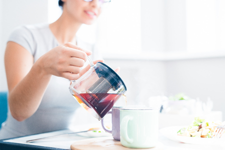 Woman Pouring Tea in Cafeの写真素材