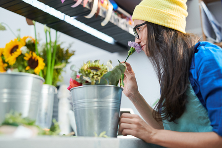 Young Woman Smelling Flowers in Shopの写真素材