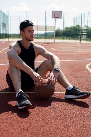 Young Man Resting in Basketball Courtの写真素材