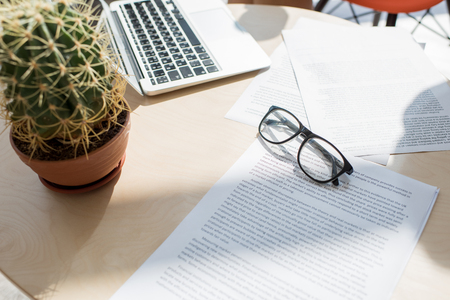 Above view closeup of elegant black rim glasses lying over documents on table in office lit by sunlight, copy spaceの写真素材