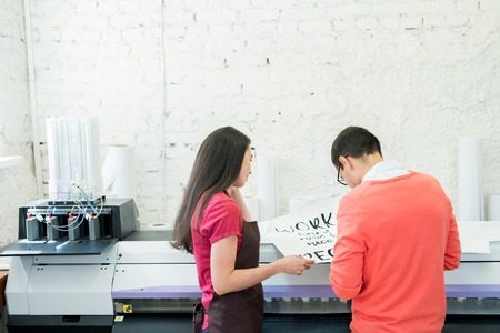 Printing specialists examining banner in officeの写真素材