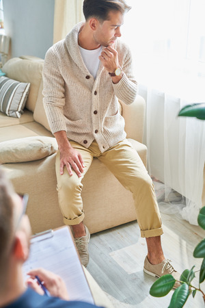 Thoughtful man focusing on his problem at therapy sessionの写真素材