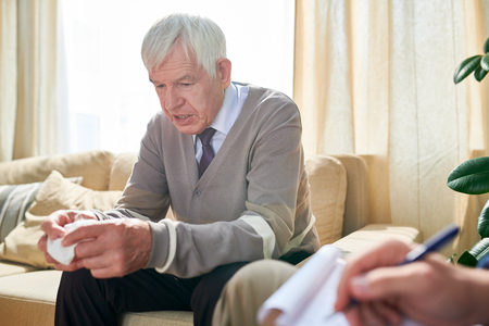 Elderly man talking about his problems at psychotherapyの写真素材