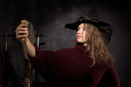 Young lady in witch costume taking selfieの写真素材
