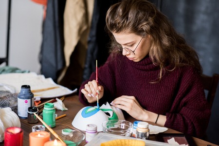 Skilled woman painting mask at tableの写真素材