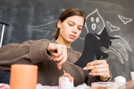 Busy girl cutting witch out of paperの写真素材