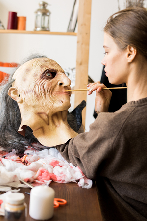 Serious girl applying paints on maskの写真素材