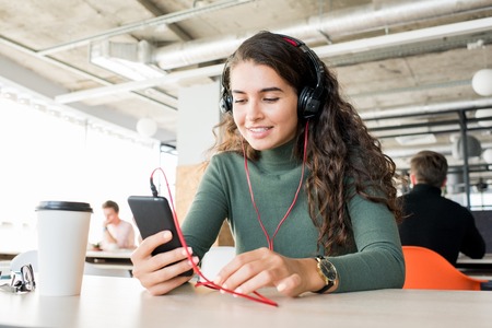 Happy girl using mobile app in open space officeの写真素材