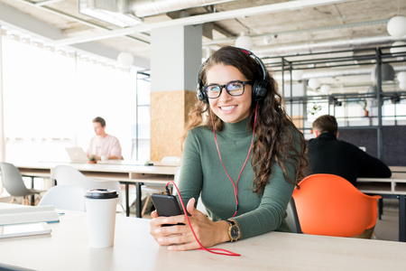 Excited female manager listening to music at workplaceの写真素材