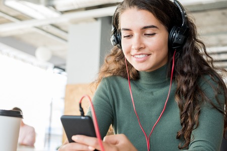 Smiling girl using music app on phoneの写真素材