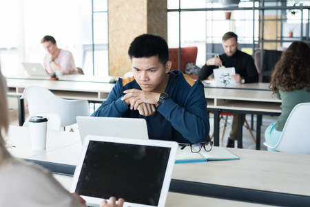 Thoughtful Asian student in coworking spaceの写真素材