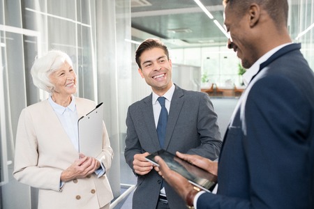 Cheerful business partners laughing while talking in officeの写真素材