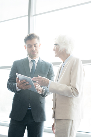Pensive man listening to recommendations from senior businesswomの写真素材