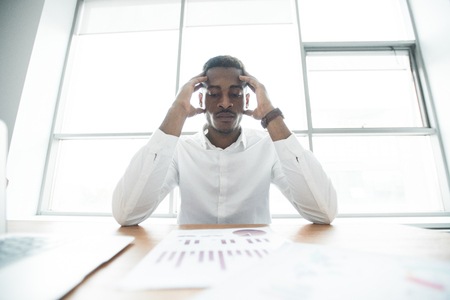 Puzzled African businessman analyzing graphsの写真素材