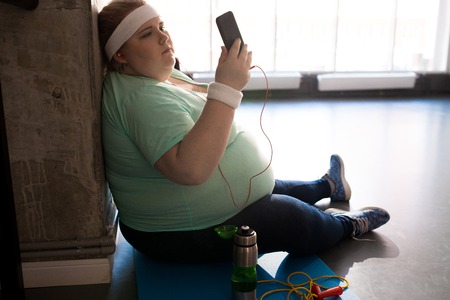 Fat Woman Using Smartphone after Workoutの写真素材
