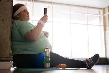 Obese Woman Using Smartphone after Workoutの写真素材