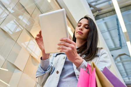 Attractive lady using tablet while doing shoppingの写真素材