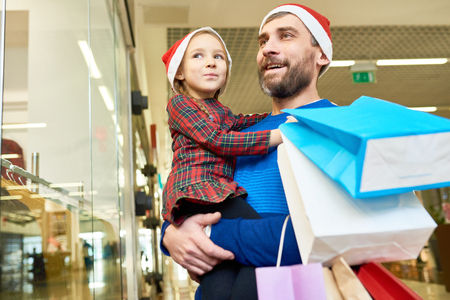 Man and girl in Santa hats shopping togetherの写真素材