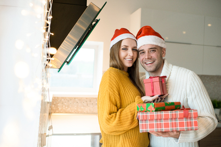 Smiling couple with New Year presents in kitchenの写真素材