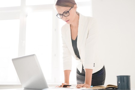 Concentrated female manager viewing data on laptopの写真素材