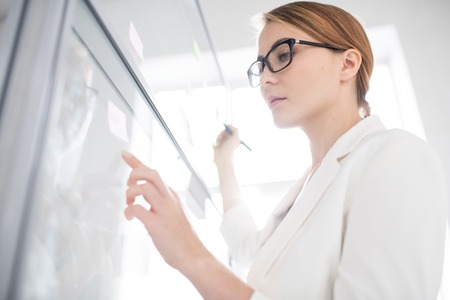 Serious businesswoman drawing on whiteboardの写真素材