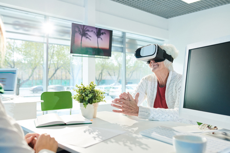 Happy senior lady in VR simulator enjoying virtual tourの写真素材