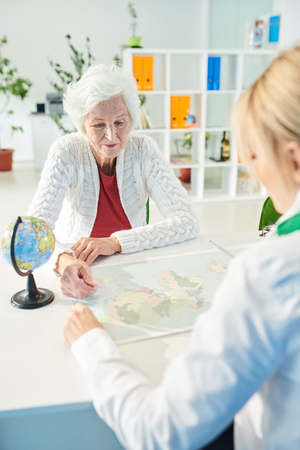 Elderly lady asking travel agent about tourの写真素材
