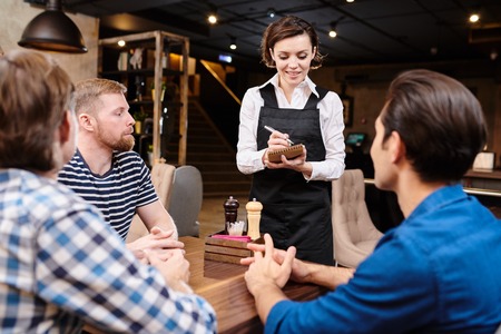 Attractive waitress talking to friends in loft restaurantの写真素材