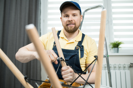 Smiling handyman screwing bolt of stoolの写真素材