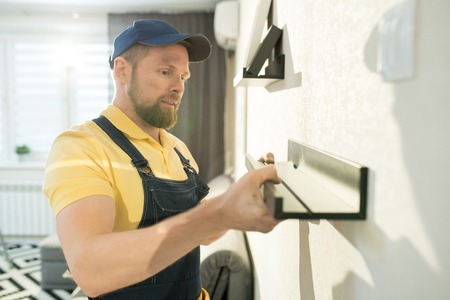 Content handyman in cap working in flatの写真素材