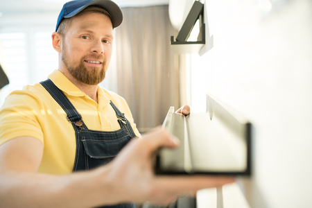Handsome handyman finding place for shelfの写真素材