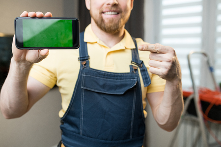 Repairman pointing at smartphone screenの写真素材