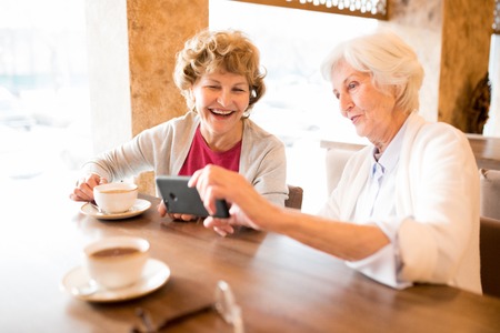Excited old ladies watching video on smartphoneの写真素材
