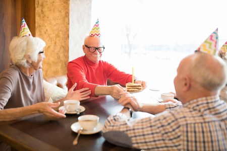 Cheerful senior people celebrating birthday of friendの写真素材