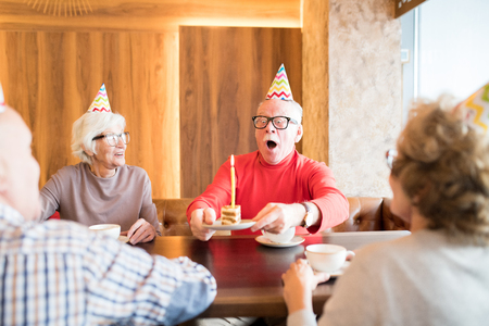 Excited elderly man blowing out cake candleの写真素材