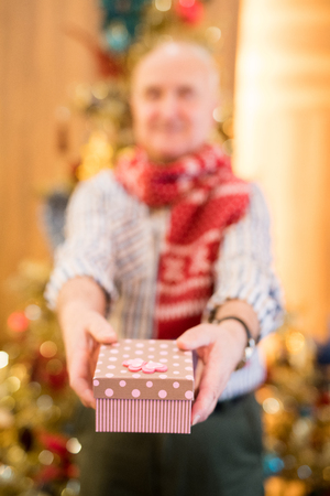 Senior man giving gift to camera