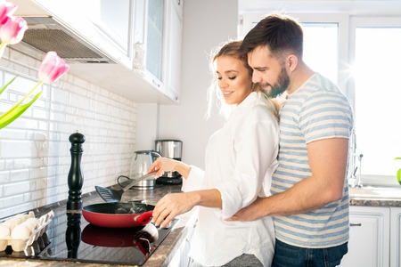 Loving Couple Cooking Breakfast in Kitchenの写真素材