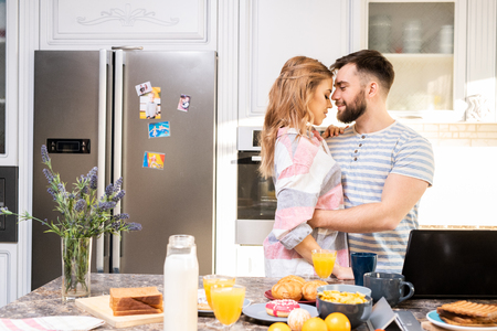Young Loving Couple Embracing in Kitchenの写真素材
