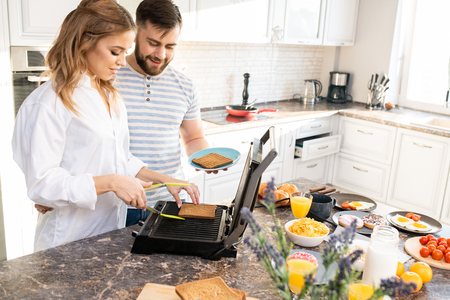 Young Couple Making Toasts in Kitchenの写真素材
