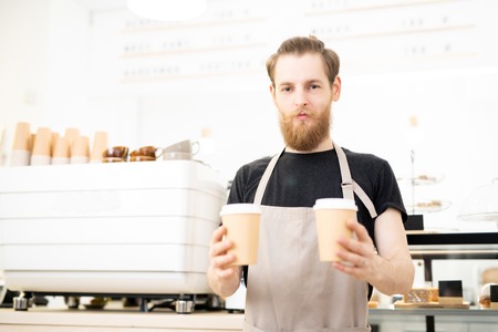 Confident barista giving takeout coffee cupsの写真素材