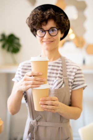 Positive lady in apron brewing tasty coffee in cafeの写真素材